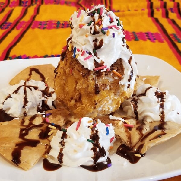 Fried ice cream with whipped cream, chocolate syrup, and sprinkles, served with tortilla chips.