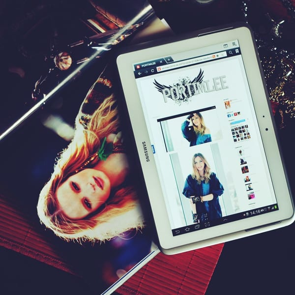 A Samsung tablet displaying a website next to a magazine with a woman's portrait.