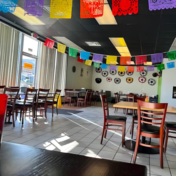 The Castañedas Mexican Restaurant dining room with colorful papel picado banners and decorative plates on the wall.