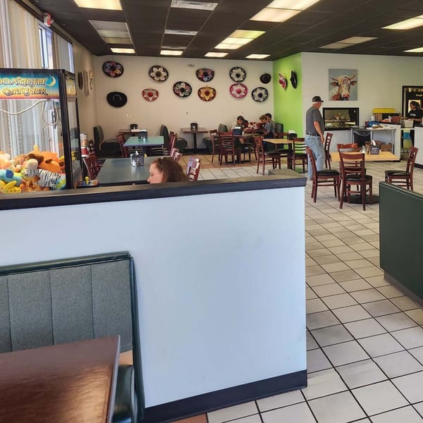Interior of Castañedas Mexican Restaurant with patrons, tables, chairs, and decorative sombreros on the wall.