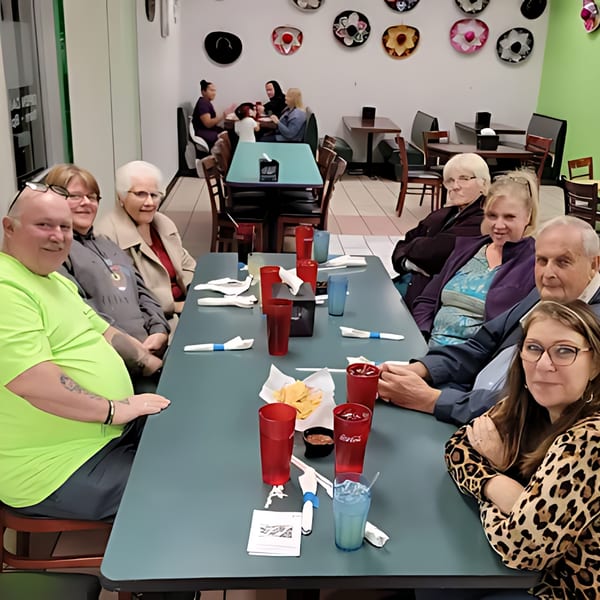 A group of people seated at a long table in Castañedas Mexican Restaurant, with drinks and chips.