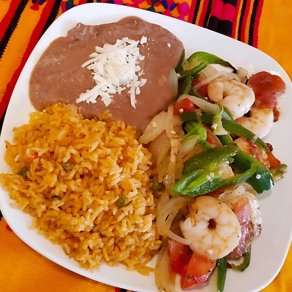 A Castañedas Mexican Restaurant plate with shrimp fajitas, refried beans, and Mexican rice.