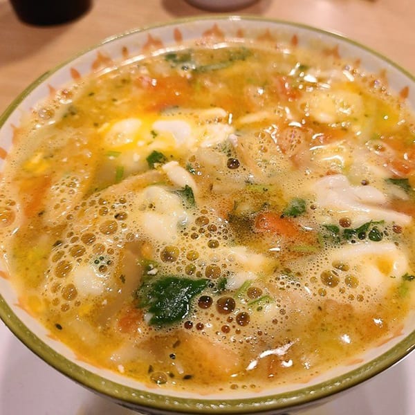 Close-up of a bowl of Castañedas Mexican Restaurant's flavorful soup with vegetables and cheese.