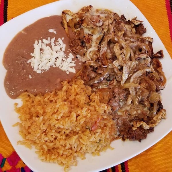 A Castañedas Mexican Restaurant plate with refried beans, rice, and a meat dish with onions.