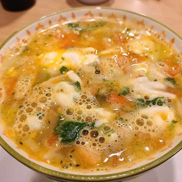 Close-up of a bowl of Castañedas Mexican Restaurant's chicken soup with vegetables and cheese.