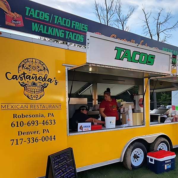 A yellow Castañeda's Mexican Restaurant food truck with two people working inside.
