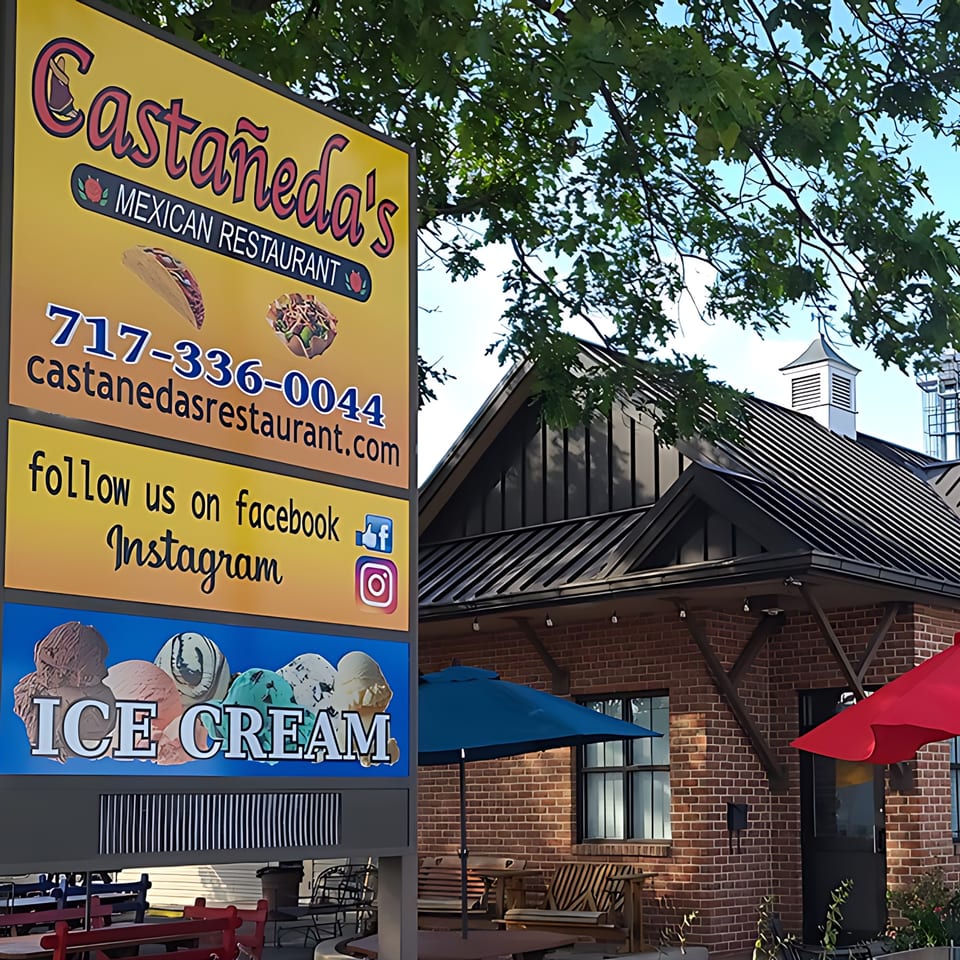 Castañedas Mexican Restaurant sign with contact info, social media, and ice cream, next to a brick building.