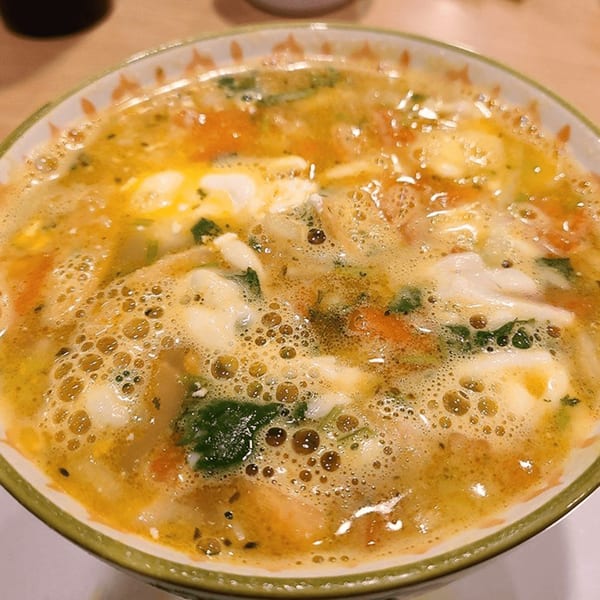 Close-up of a bowl of Castañedas Mexican Restaurant's flavorful soup with vegetables and cheese.