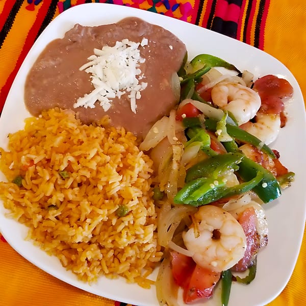 A Castañedas Mexican Restaurant plate with shrimp fajitas, rice, and refried beans with cheese.